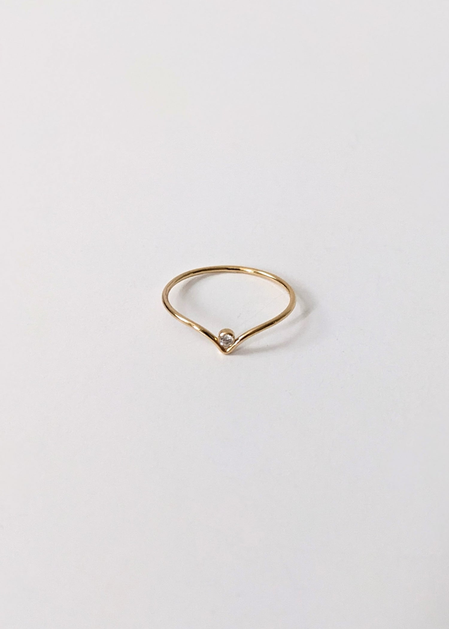 Gold ring with a small diamond on a light gray background