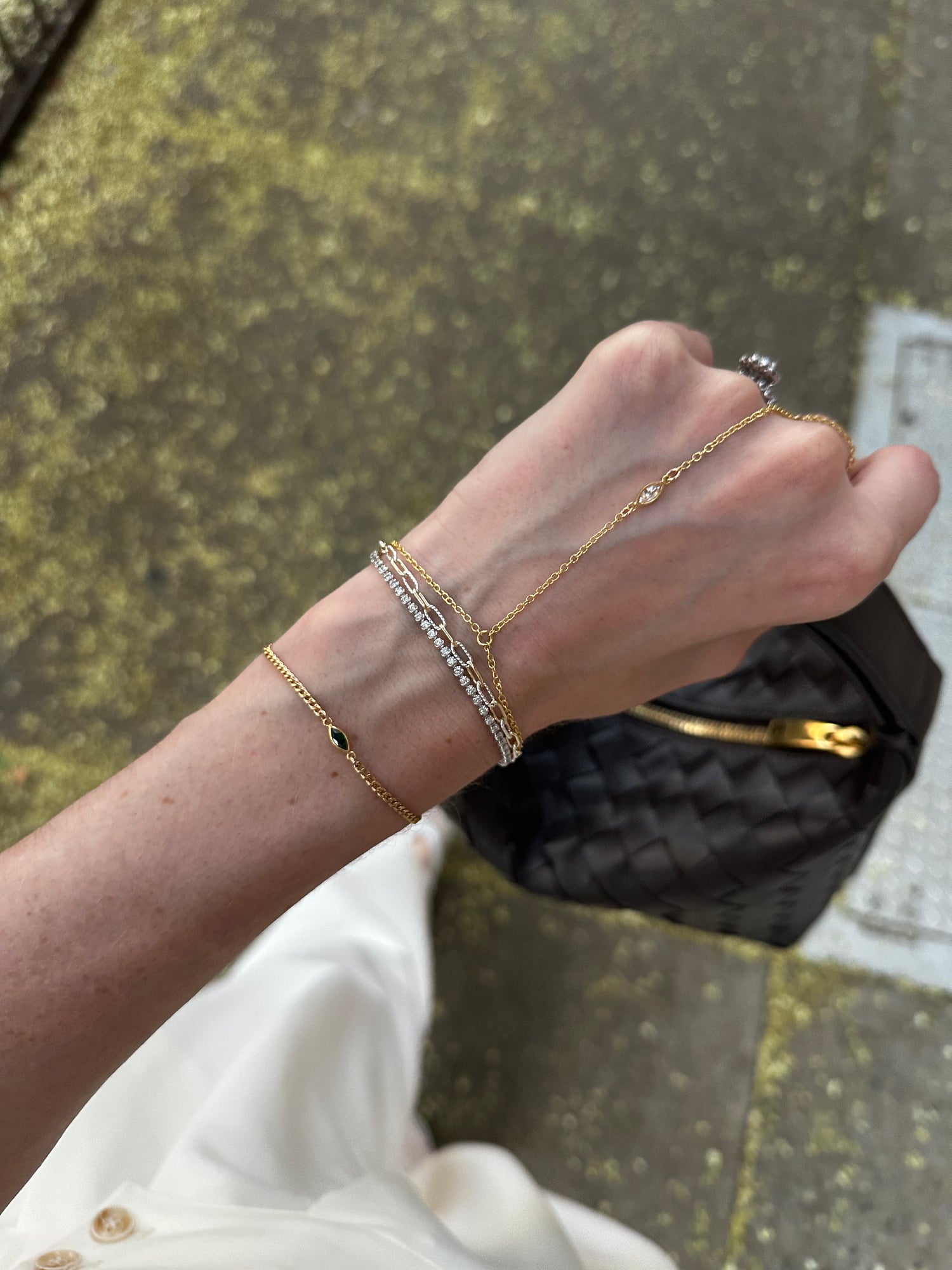 A bracelet stack featuring a gold-filled hand chain with a marquise stone, ring loop, and adjustable wrist chain stacked with gold and silver mixed metal bracelets. A delicate bracelet-style hand chain, handmade in Brooklyn by Layer the Love.