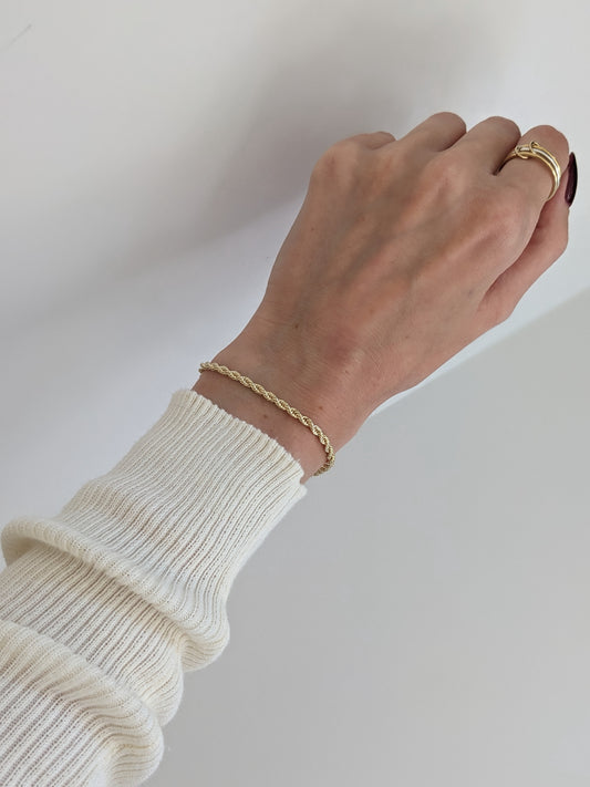 gold Rope chain bracelet modeled on the wrist completed with a ring on a neutral background
