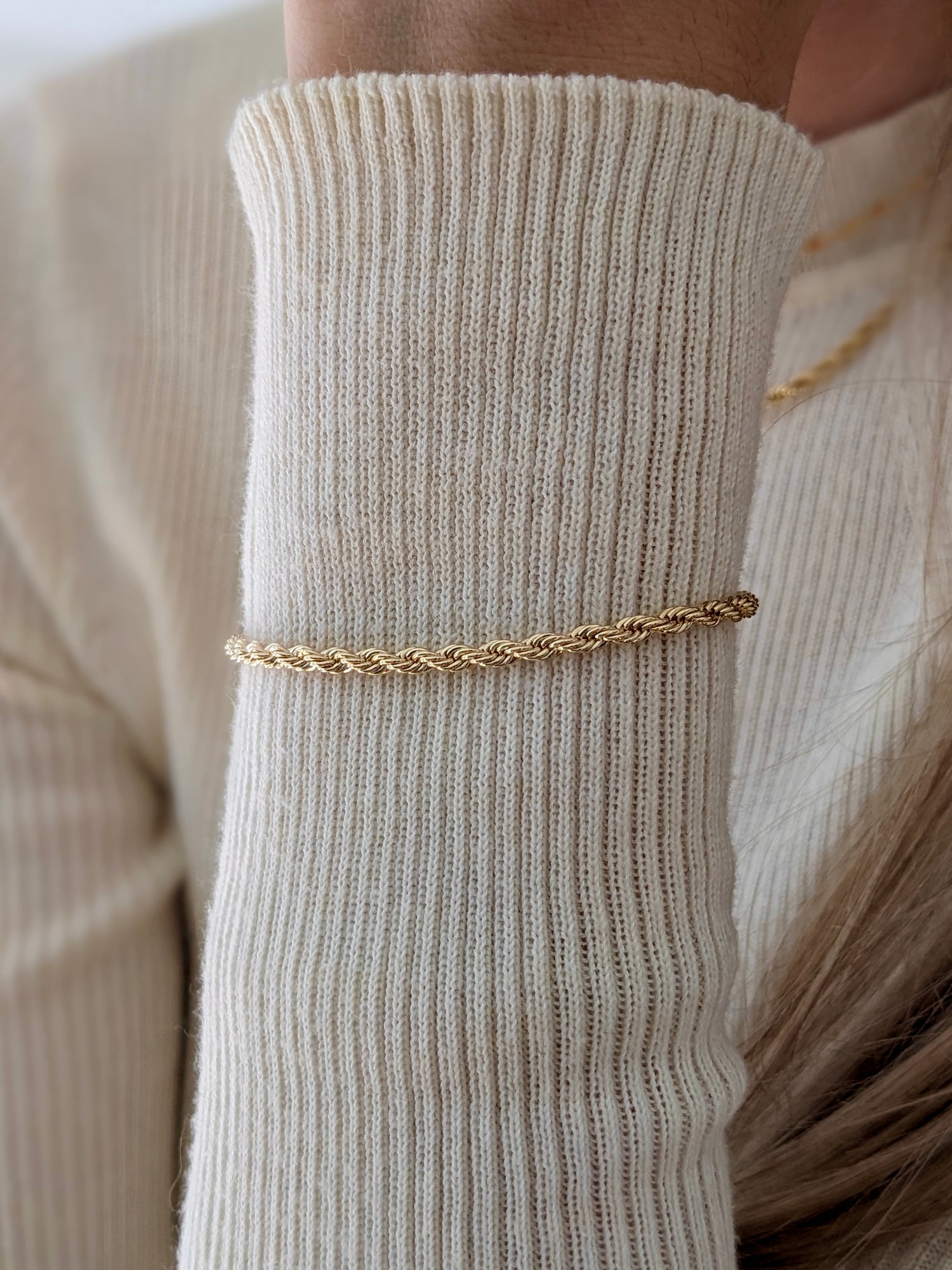 Rope chain bracelet modeled over a cream sweater