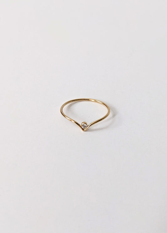 Gold ring with a small diamond on a light gray background